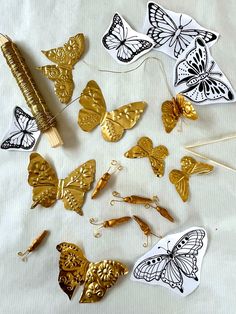 gold and black butterfly decorations on a white tablecloth with pins in the shape of butterflies