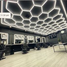 the interior of a hair salon with chairs and mirrors on the walls, lights in the ceiling