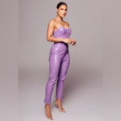 a woman in a purple leather outfit posing for a photo with her hand on her hip