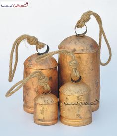 three antique brass bells with rope hanging from the top and bottom, on a white background