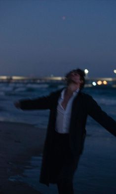 a man standing on top of a beach next to the ocean