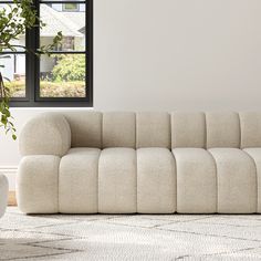 a white couch sitting on top of a rug next to a window