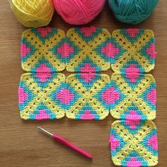 balls of yarn and crochet sitting on top of a wooden table