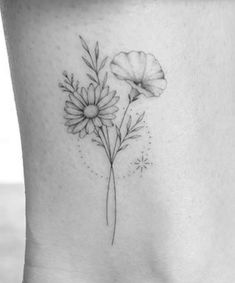 a small flower tattoo on the side of a woman's stomach, with leaves and flowers