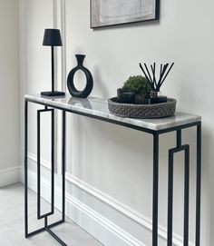 a console table with two black vases on it