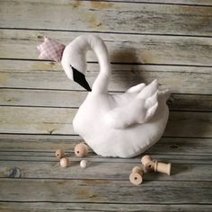 a white swan sitting on top of a wooden floor next to some wood pegs