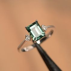 a ring with an emerald and diamonds on it