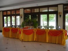 a banquet table set up with orange and yellow drapes