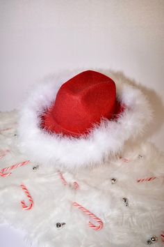 a red hat sitting on top of a pile of white fur with candy canes