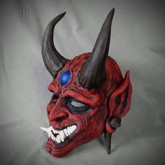 a red mask with horns and blue eyes