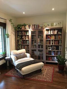 a living room filled with lots of furniture and bookshelves next to a window