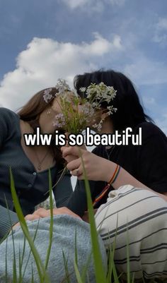 two women laying on the ground with flowers in their hands and one woman is kissing her face