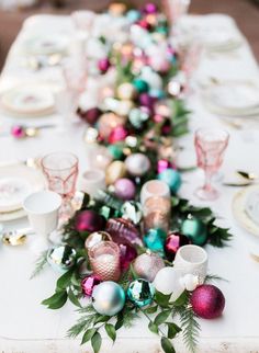 the table is set with pink and green ornaments, silverware, and white dishes