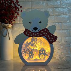 a light up teddy bear with a red scarf on it's neck sitting in front of a brick wall