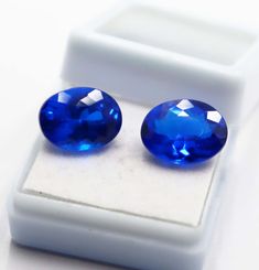 pair of blue sapphires sitting on top of a white box