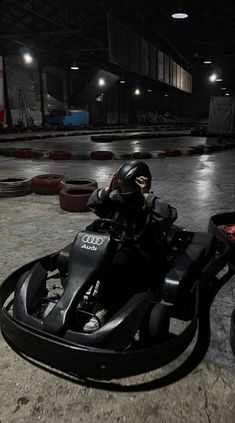 a man riding on the back of a black motorcycle in a parking lot at night