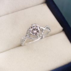 a diamond ring sitting on top of a white velvet cushioned surface in a box