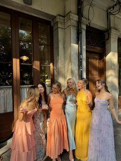 a group of women standing next to each other in front of a building