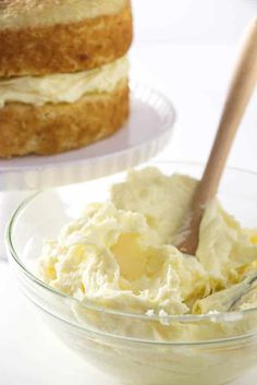 a glass bowl filled with whipped cream next to a cake