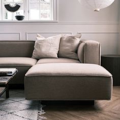 a living room with a couch, coffee table and lamp hanging from the ceiling above it