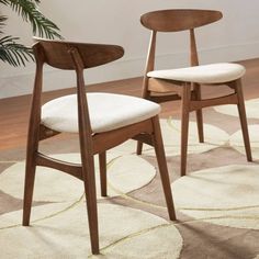 two wooden chairs sitting on top of a rug