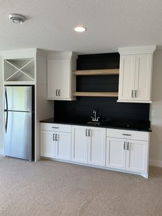 an empty kitchen with white cabinets and black counter tops