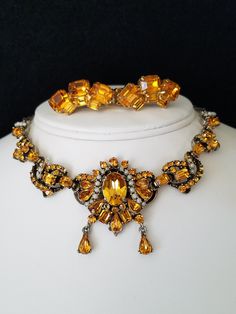 "This necklace not only has beautiful Yellow Emerald cut stones but also tiny White peals which are handset into open bezel caps and than prong set. It is marked \"Hollycraft\" on the back, but also has a dated, \"Copr. 1953.\" According to Maryanne Dolan author of Collecting Rhinestone & Colored Jewelry,\" dated jewelry is rare\". The necklace is crowed with various sizes and shapes of colored Yellow Rhinestones and Seed Pearls. Some even go as far to say that Hollycraft Jewelry is Hollywoo Vintage Gold Necklaces With Matching Earrings, Vintage Gold Necklace With Matching Earrings, Vintage Jewelry Sets With Matching Earrings For Formal Events, Vintage Jewelry Sets With Matching Earrings For Formal Occasions, Vintage Jewelry Sets For Wedding, Vintage Wedding Jewelry Sets With Jewels, Yellow Costume Jewelry For Formal Occasions, Vintage Metal Jewelry Sets For Parties, Vintage Yellow Metal Jewelry