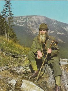 an old photo of a man with a long beard sitting on top of a hill