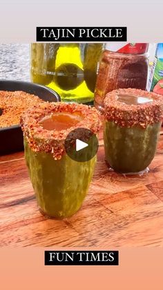 two jars filled with pickles sitting on top of a wooden table next to each other