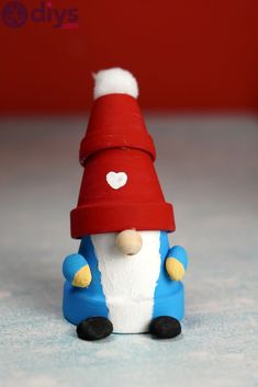 a small figurine with a red hat and blue jacket sitting on top of a table