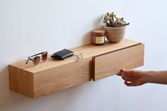 a wooden shelf with sunglasses, cell phone and other items on it next to a wall