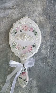 an ornate white plate with pink roses on it and a ribbon tied around the edge