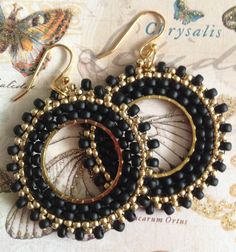 two pairs of black beaded earrings on top of a piece of paper with butterflies in the background