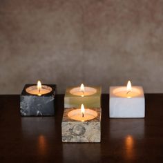 three square candles sitting on top of a wooden table