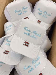 a box filled with white hats that say from florida to florida, and have blue lettering on them