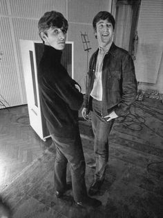 two young men standing next to each other in front of a television screen with wires on the wall behind them