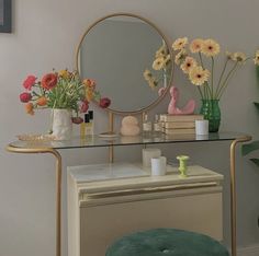 a vanity table with flowers and candles on it next to a mirror, stool and vase