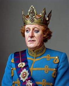 an old man in a blue uniform with a crown on his head