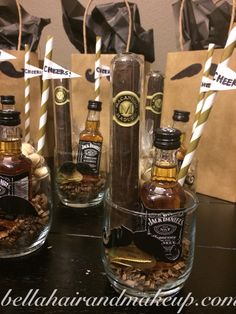 three bottles of whiskey sitting on top of a table next to paper bags with straws in them