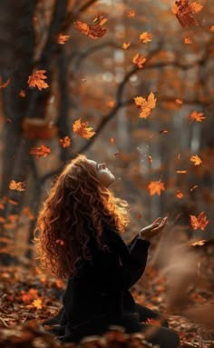 a woman is sitting in the leaves with her eyes closed and looking up into the sky