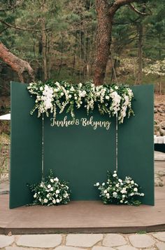 an outdoor ceremony setup with flowers and greenery on the back wall, hanging from chains