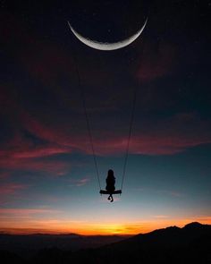 a person on a swing in the sky at night with a crescent moon behind them