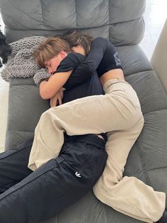 two people sleeping on a couch with their arms around each other