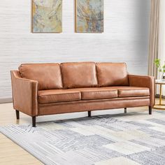 a brown leather couch sitting on top of a rug