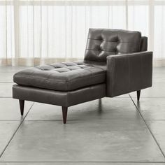 a brown leather chaise lounge chair sitting on top of a tile floor next to a window