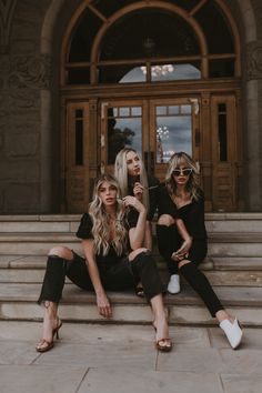 three women sitting on steps in front of a building