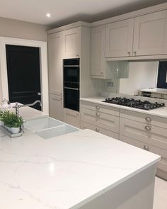 a large kitchen with white cabinets and marble counter tops on the island in front of an oven