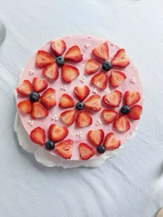 a cake with strawberries and blueberries on it sitting on top of a table