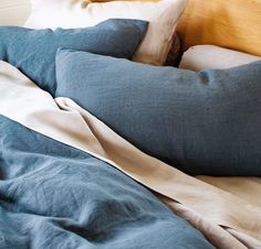 an unmade bed with blue sheets and pillows