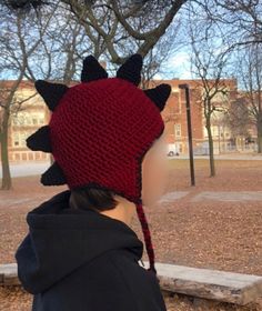 a woman wearing a red knitted hat with black horns on it's head